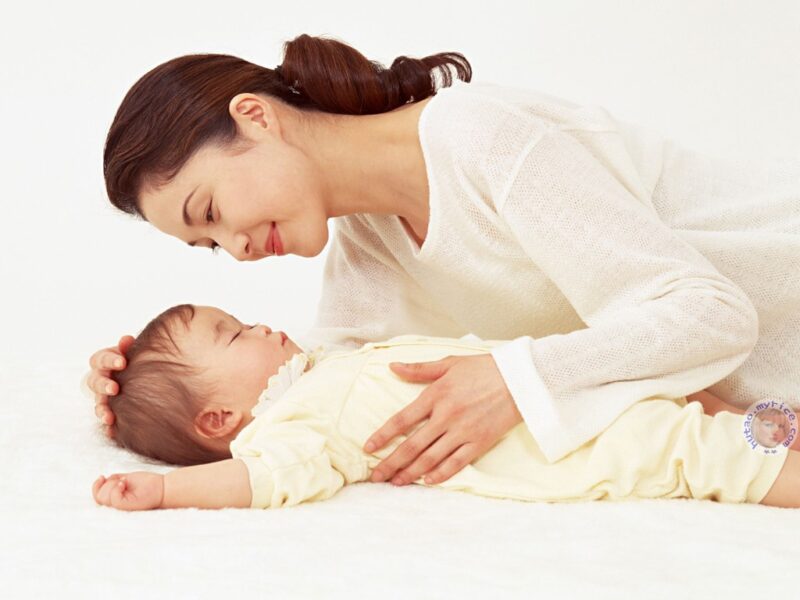 Bild einer Mutter, die ihr Baby vor hellem Hintergrund in den Schlaf wiegt