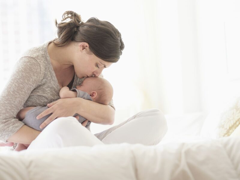 Das Bild einer Mutter, die ihr Baby in den Schlaf wiegt und es küsst